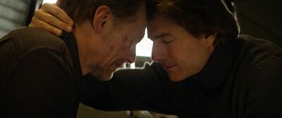 Two men sit with their heads together.