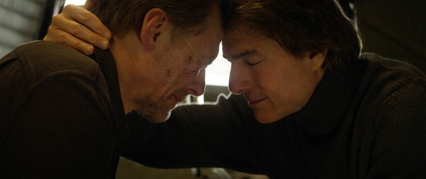 Two men sit with their heads together.