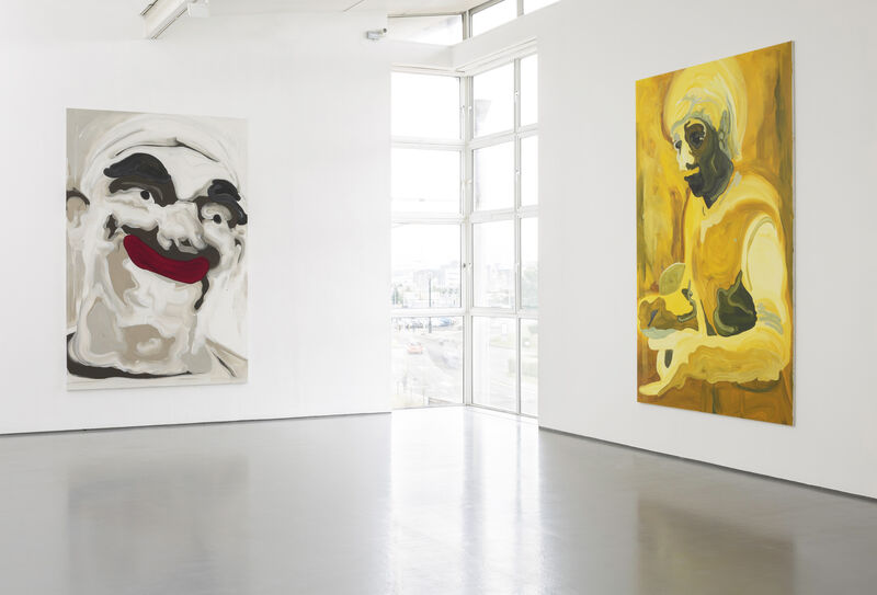 Installation view of Gallery 1 with bright natural light and white walls. To the left is a painting mostly in white of a clownish face with dark eyebrows and bright red lips.On the right is a mostly yellow painting of a figure's upper body. The paint strokes are bold and broad.  