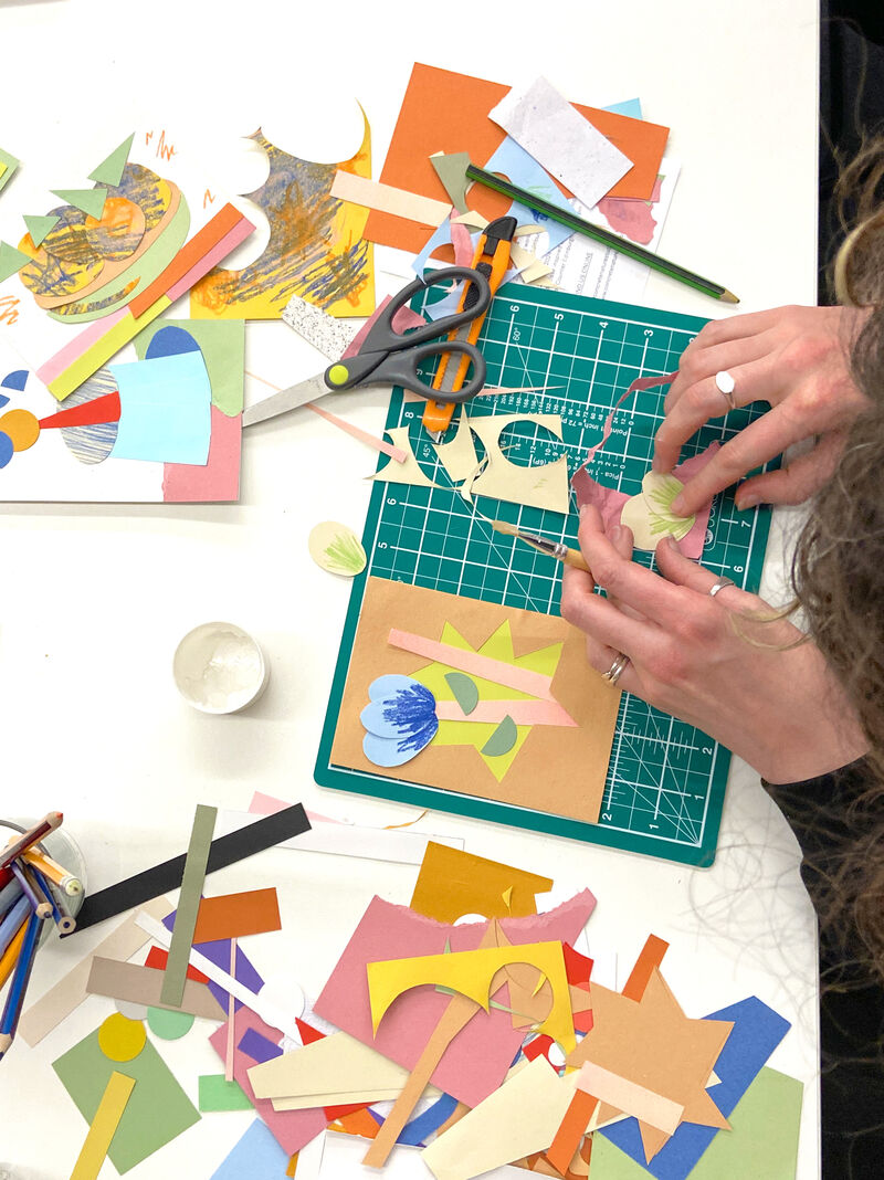 Person creating a collage surrunded by colourful paper