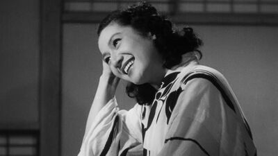 A black and white film still of a woman smiling.