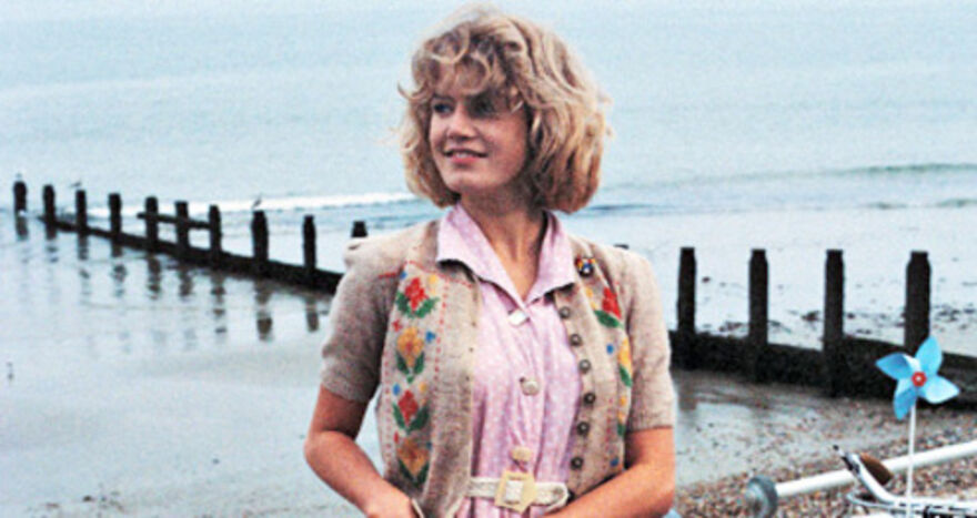 A girl stands in front of the sea with a 80s style