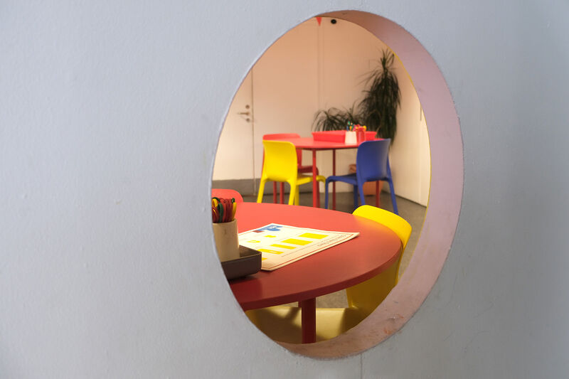 Circle window in play box with colourful chairs and tables on the other side