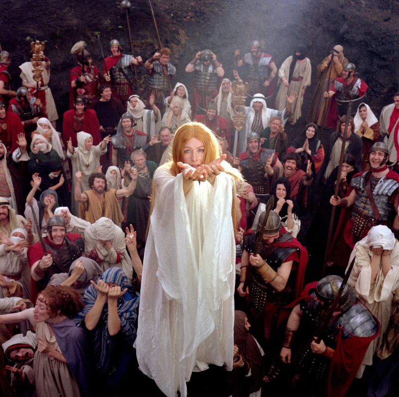 A woman with long hair and a long white dress floating above a crowd