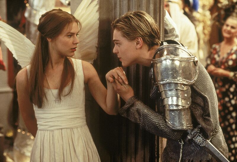 A young man dressed in a suit of armour holds the hand of a young woman dressed as an angel