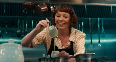 A woman smiles as she ladles a drink into a glass