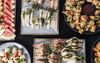 A table laid with a plates of food: sandwiches, fruit, battered brocolli, and sweet things