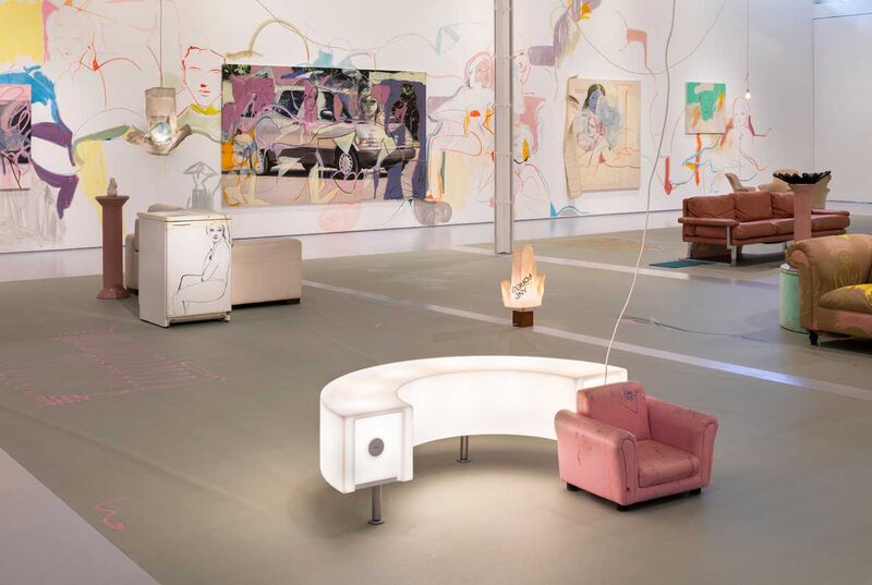 A gallery space with bright paintings on the wall, with paint directly on the walls - in the centre of the gallery are a Lightbox and a small armchair 