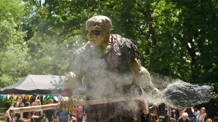 The Toxic Avenger holding a steaming broom at an outdoor fete