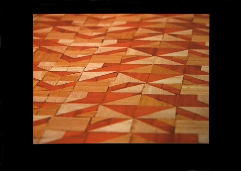 From Cara Tolmie's exhibition. A floor is tiled with a geometric, triangular pattern in orange, red, yellow and cream. 