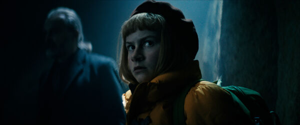 A girl in a beret walks in a dark, spooky forest