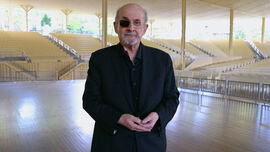 Author Salman Rushdie stands in an empty venue