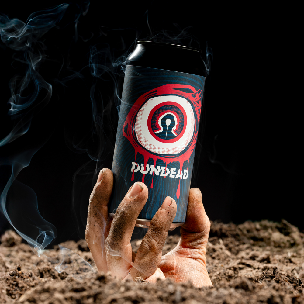 Hand coming out of the ground holding a can of Dundead IPA by Holy Goat