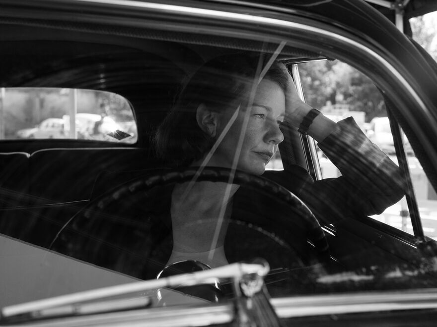 A woman leans out of the window of her car