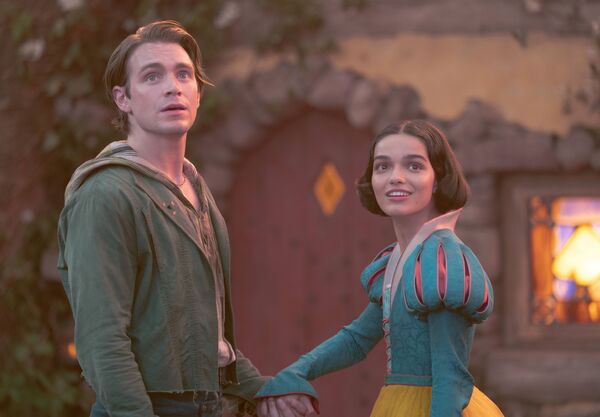 Snow White and Prince Charming stand outside a cottage smiling.