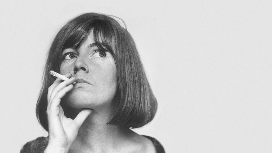 A woman with a bob smokes a cigarette and looks up