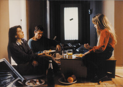 Parents and a young girl sit on the floor of an empty apartment eating breakfast quietly.