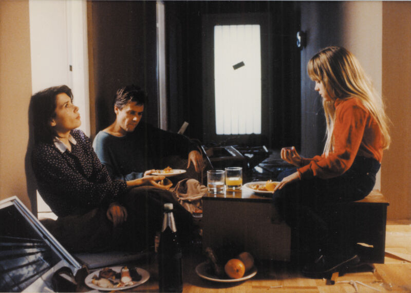Parents and a young girl sit on the floor of an empty apartment eating breakfast quietly.
