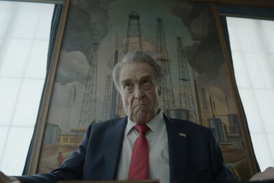 The President of the US sits looking unhappy in front of. painting of oil wells