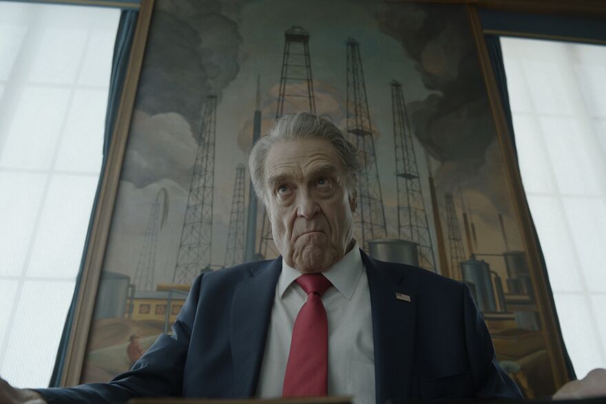 The President of the US sits looking unhappy in front of. painting of oil wells