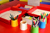 Pots with pens, pencils and crayons beside trays of My Family Rug activity sheets in DCA Create Space