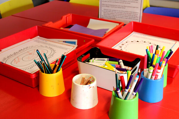 Pots with pens, pencils and crayons beside trays of My Family Rug activity sheets in DCA Create Space