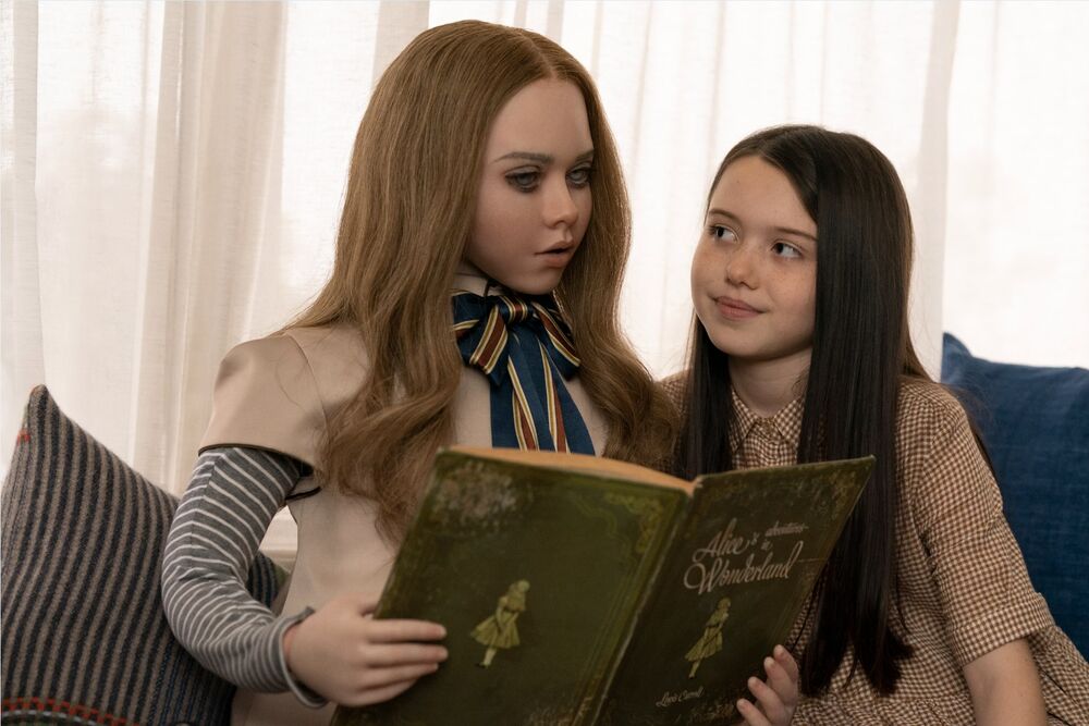 A humanoid robot with blonde hair reads to a young girl