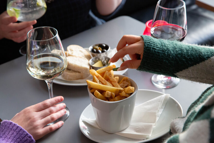 Bowl of chips on a table with person reaching for one