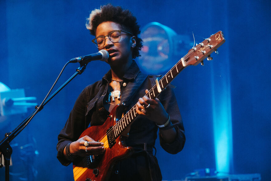 A woman sings and plays guitar on stage