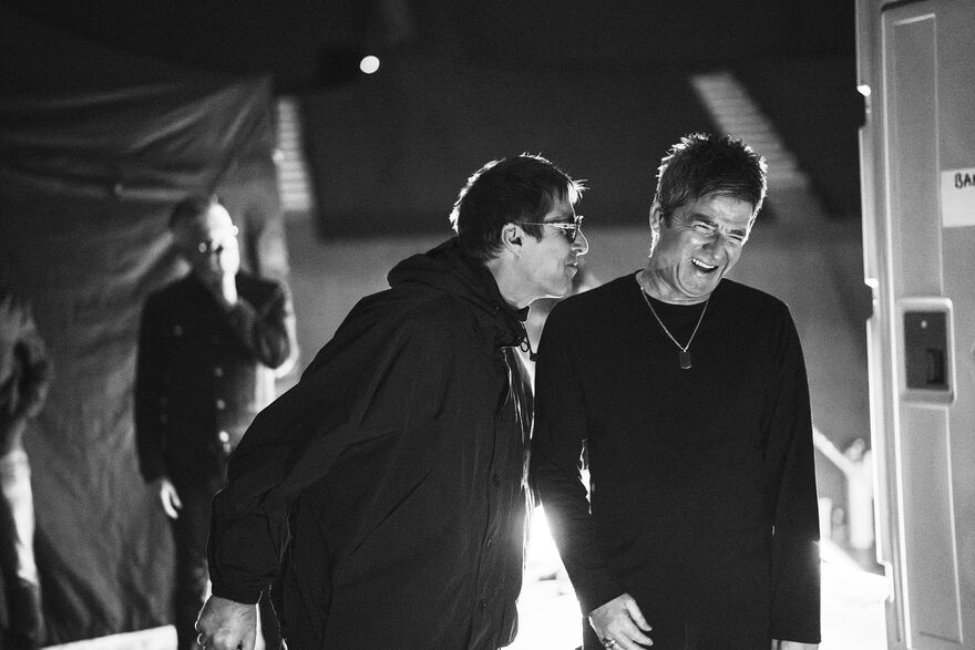 Liam and Noel Gallagher laughing backstage
