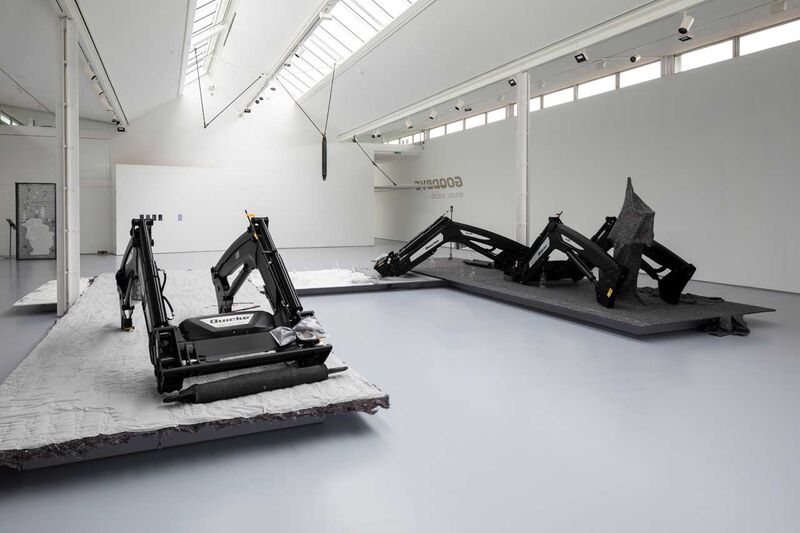 Large farm equipment sitting on a plinth in a gallery space