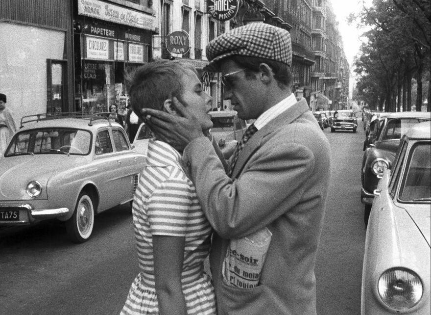 A man and woman in sixties clothing embrace on a city street