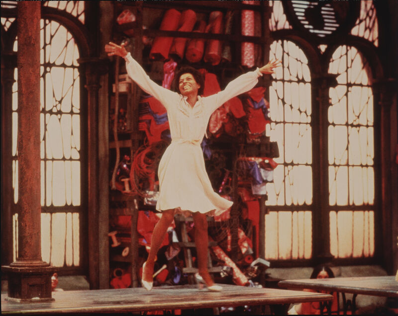 A young black women in a white dress with her arms extended wide