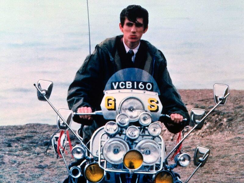 Phil Daniels on a motorbike on the beach.
