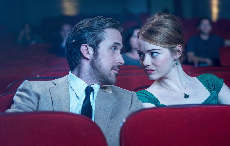 A man and woman smile at each other in the cinema
