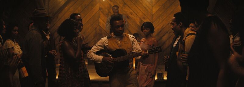 A man plays a banjo in a 1930s-style party.