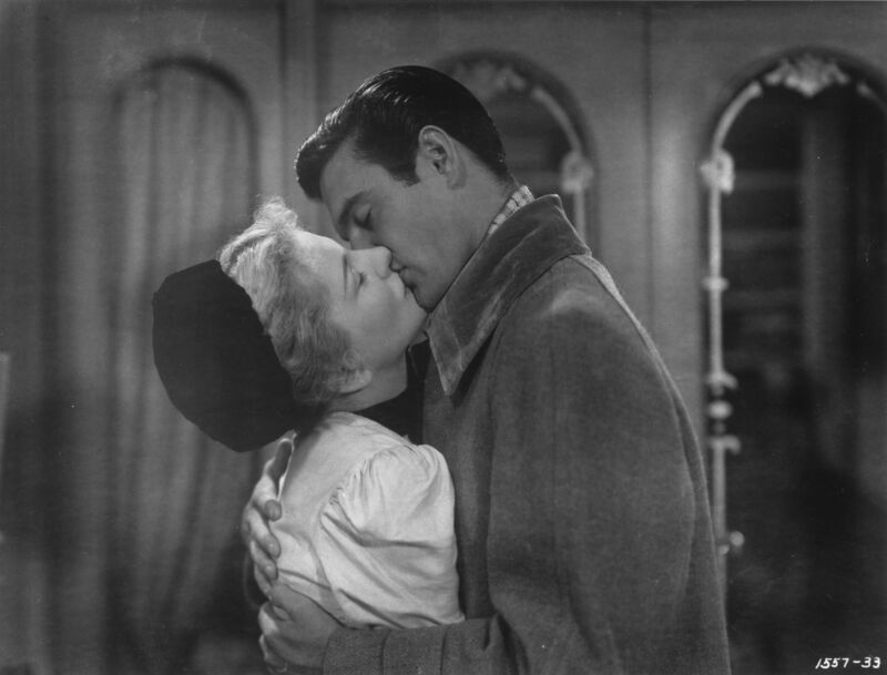 A man and woman kiss in a scene from a 1940s film.