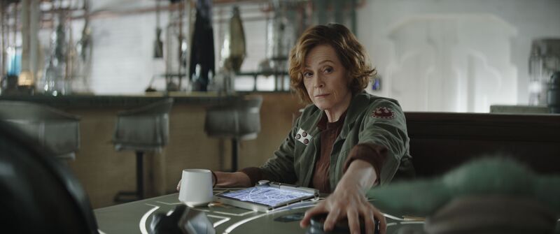 Sigourney Weaver sits at a table in Star Wars: The Mandalorian and Grogu.