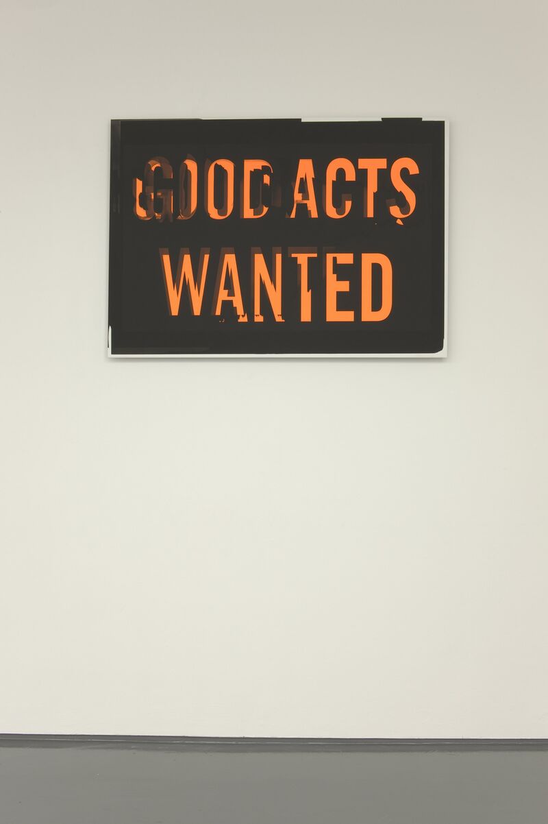 A black canvas from Scott Myles' 2012 exhibition. In large orange text, it says 'GOOD ACTS WANTED'