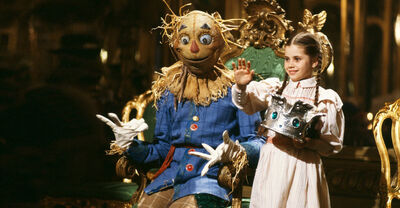 Dorothy waves as she crowns the Scarecrow