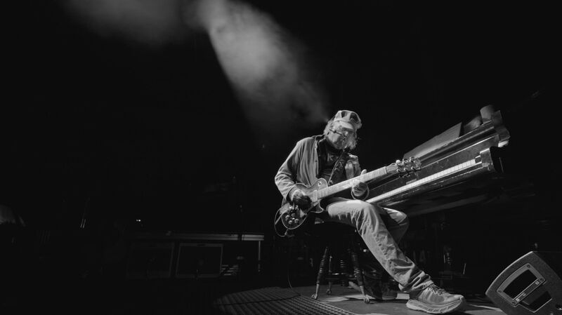 Neil Young plays guitar on stage.