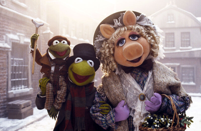 A still from the Muppets Christmas Carol shows Miss Piggy, Kermit, and a little version of Kermit.