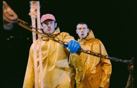 Two men in yellow waterproof jackets on a fishing vessel.