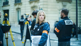 A policewoman carrying a folder looks around at a crime scene