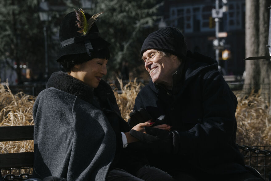 A woman and a man laugh on a park bench