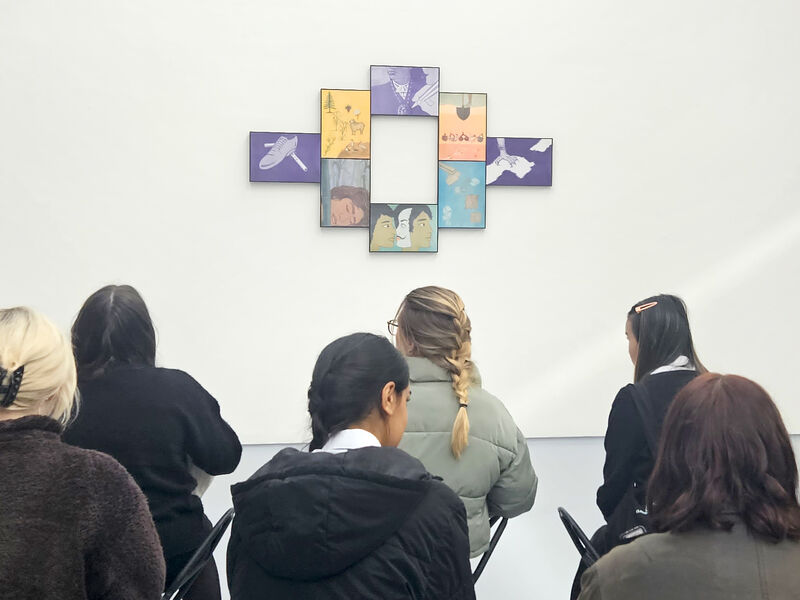 Secondary school pupils sitting on stools in DCA galleries looking at printed artwork on the wall