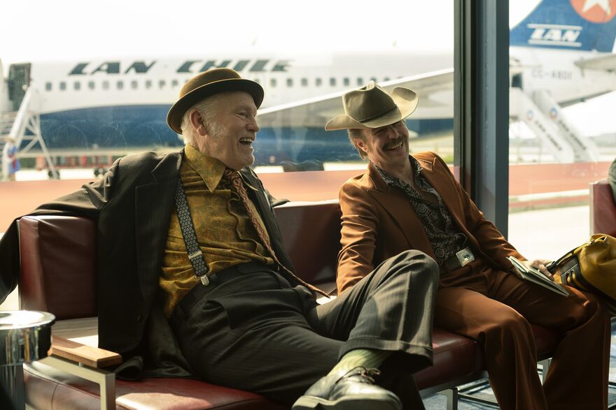 Two men laugh in an airport