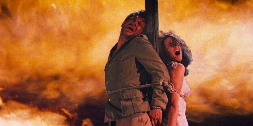 Indiana Jones is tied to a stake with his sidekick Marion. They shut their eyes and scream.