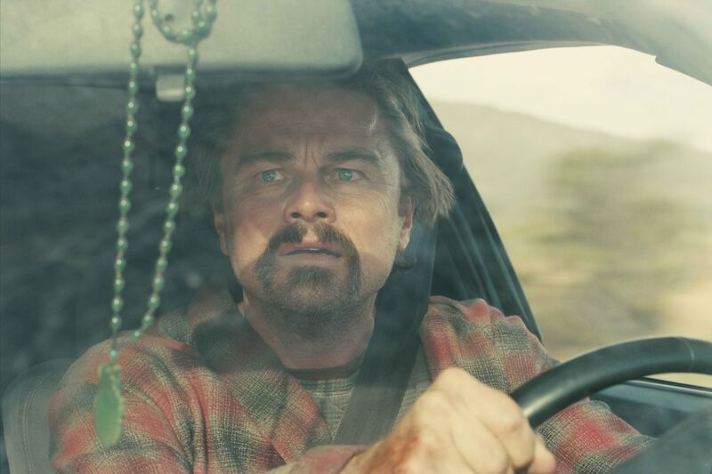 A man looks anxiously at rosary beads while driving a car