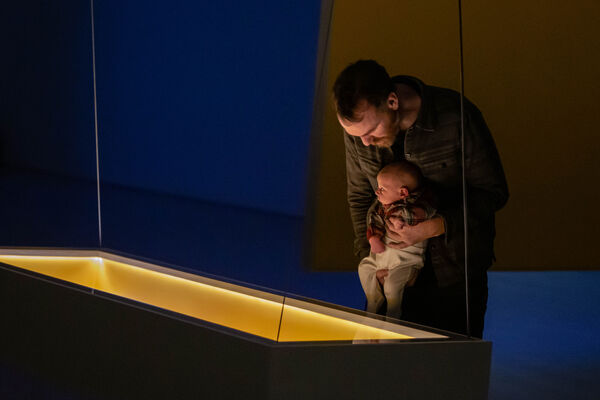 Man holding a baby over a glowing display case in DCa Galleries